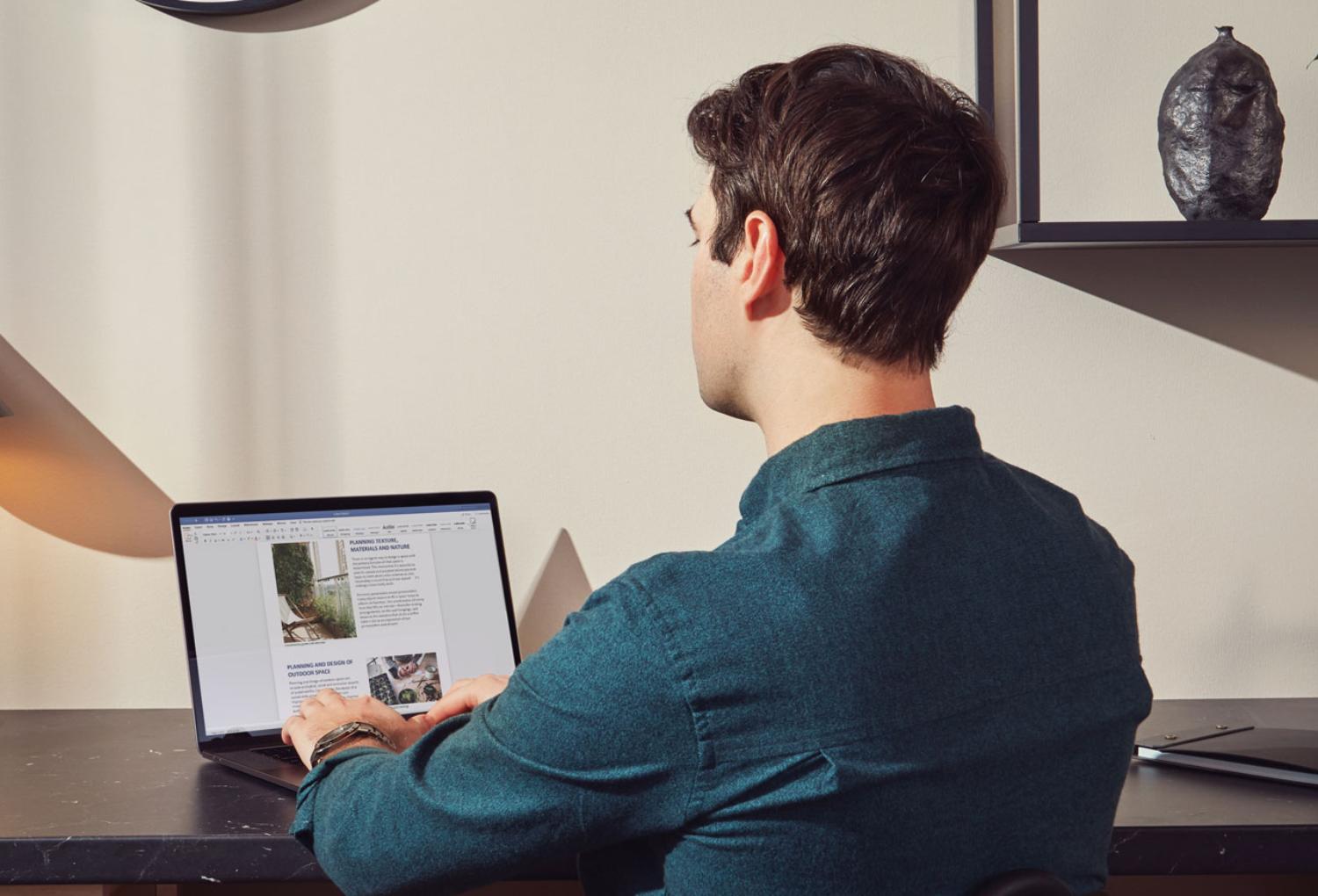 Person using an iPad with a stylus while seated at a table in a casual environment