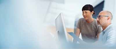 A man and woman looking at a computer screen.