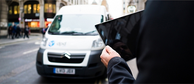 A man holding a tablet in front of a van.