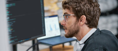 A man in glasses is looking at a computer screen.