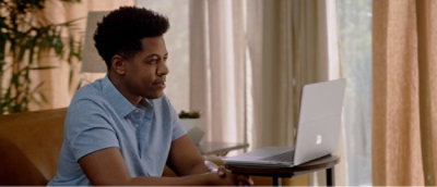 A focused man sitting at a table working on a laptop in a well-lit room