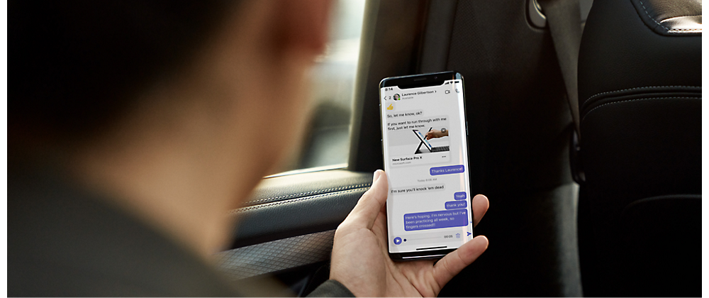 Person in a car checking a smartphone with a messaging app open.