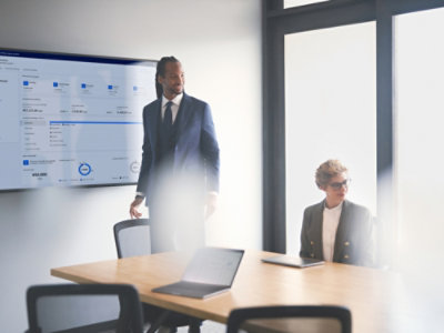 A man in a suit standing in front of a boardroom table.