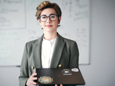 Person holding a laptop and standing in front of a whiteboard.