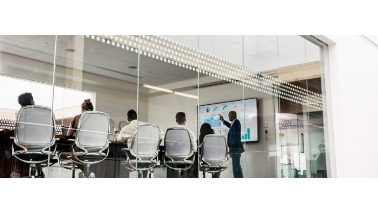 A group of professionals in a modern, well-lit conference room, focusing on a presentation displayed on a large screen