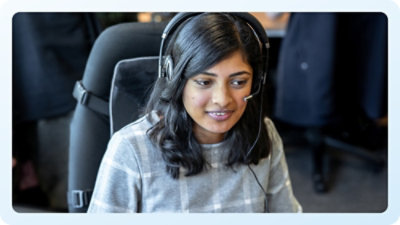 A woman wearing headphones and talking on a computer.