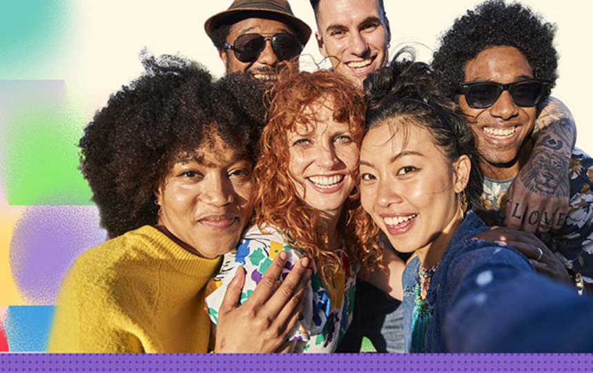 Six smiling people standing close together for a selfie outdoors in bright daylight.