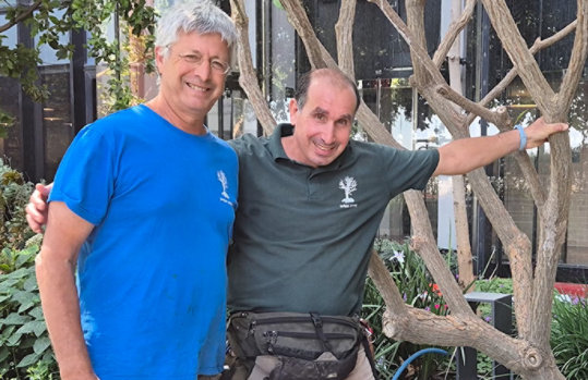 Two men standing next to each other with an arm around one another, smiling