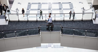 מבט אווירי על הלובי הפנימי של הבניין. שני גברים הולכים על מסלול מוגבה. גבר ואישה על מדרגות נעות, ואנשים אחרים הולכים בקומת הקרקע למטה.