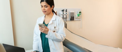 Oseba v beli halji drži telefon.