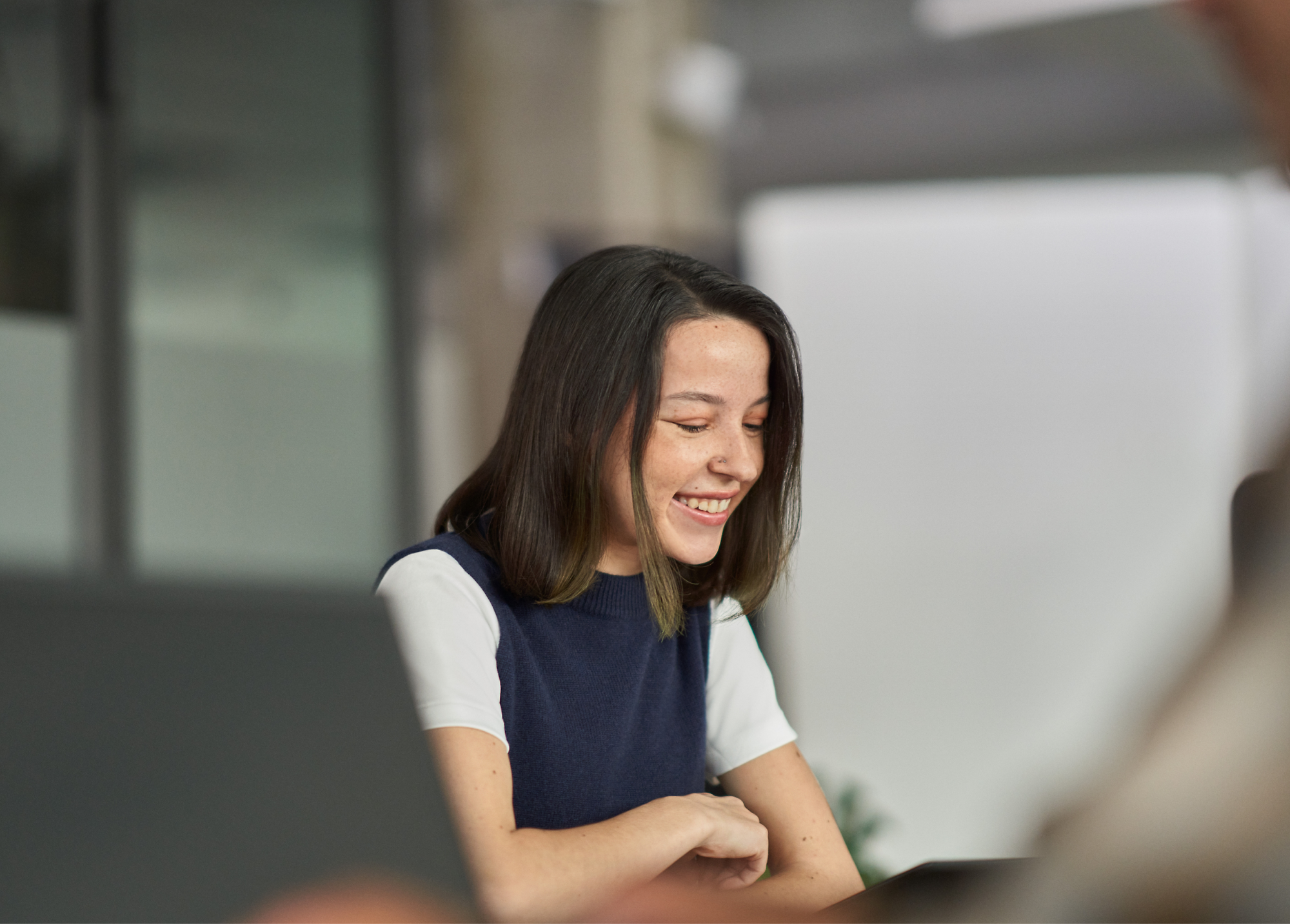 Žena sa usmieva počas schôdze v kancelárskom prostredí.