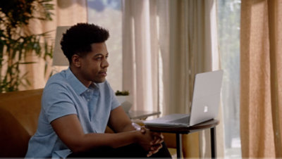 Uomo seduto che guarda un portatile.