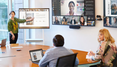A group of people in a meeting, with a girl describing a presentation to two other individual