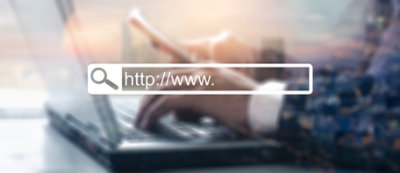 Osoba kuca na laptop računaru i koristi pametni telefon, sa prekrivenom trakom za pretragu koja prikazuje „https://www.