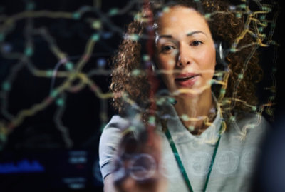 Person interacting with a digital network visualization displayed on a transparent screen.