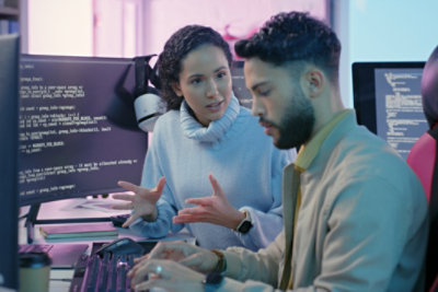 Two people working together while reviewing code on computer screens.