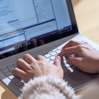 Mains tapant sur le clavier d’un ordinateur portable pour écrire du code