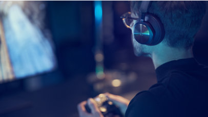 A person wearing Beoplay Portal Headphones plays a game on Xbox.