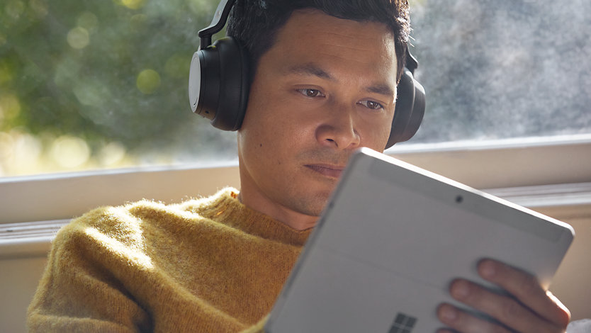 A person using a Surface tablet with a headset.