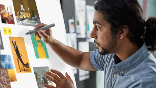 A person uses a Surface Hub 2 Pen to digitally draw on their Surface Hub 2 S.