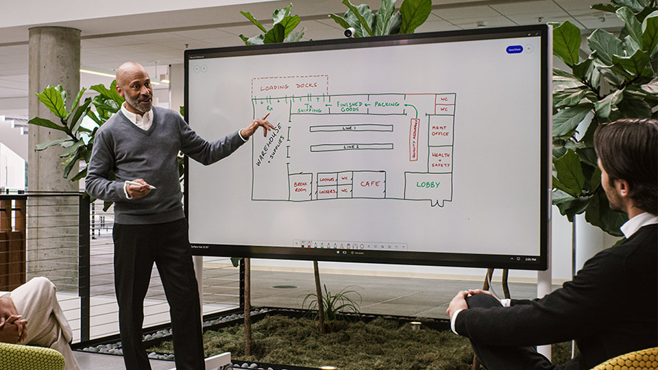 A person uses the Surface Hub 2 S on a Mobile Stand in a makeshift office.