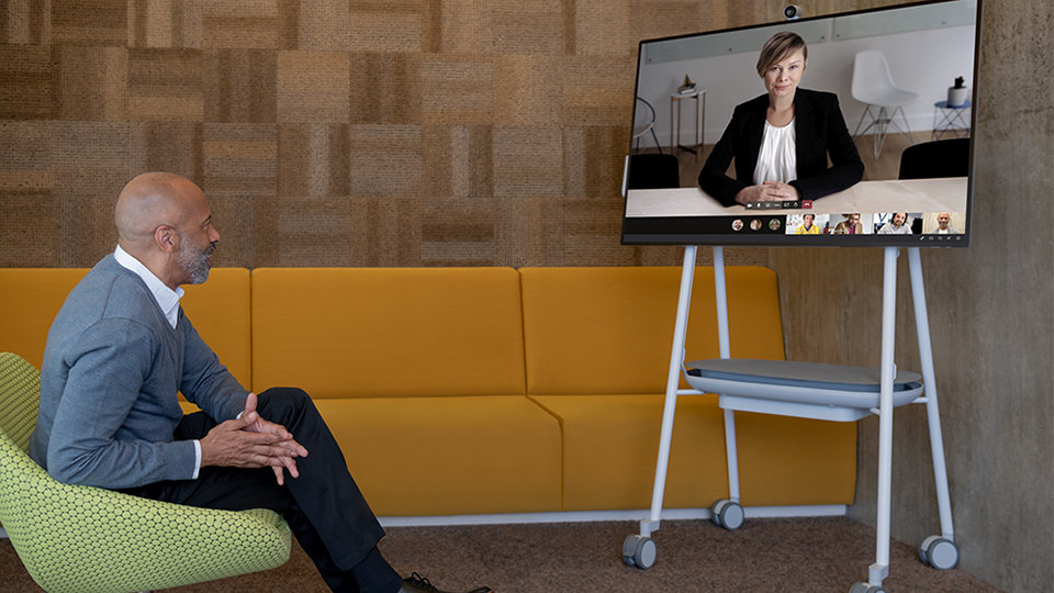 A person in an office uses the video call features on Surface Hub 2 S.