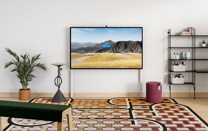 Un Surface HUB 2S 85'' en el soporte de pared con soporte para el suelo en un entorno de oficina.