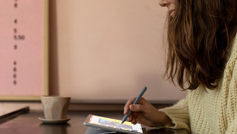 一个女人使用 Surface 触控笔在工作室模式的 Surface Go 2 上绘画