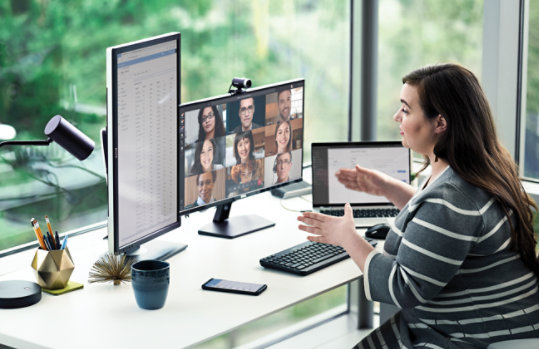 Une personne à un bureau parlant à un grand groupe dans Teams à l’écran.