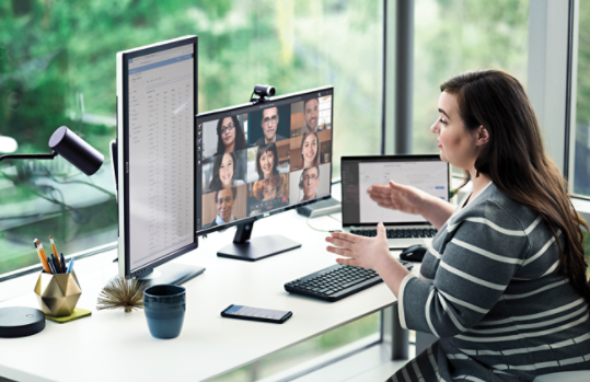 Mujer delante de unos monitores en una videoconferencia.