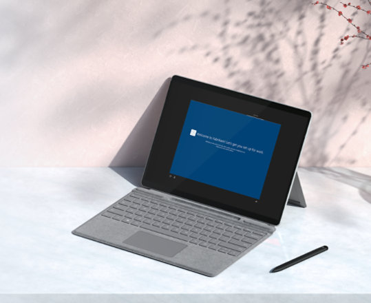 Surface device with type cover and pen on a desktop.