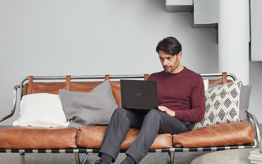 Osoba używająca programu Visio na laptopie Surface, siedząca na skórzanej sofie z poduszkami.