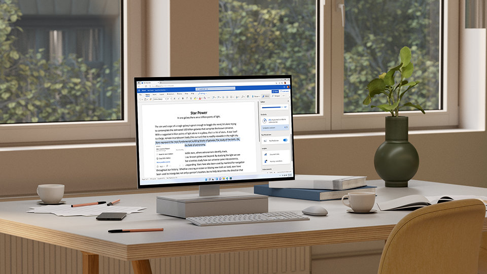 Una PC todo en uno que muestra Microsoft PowerPoint junto a una cámara, una taza de café y rollos de papel. PC con licencia Microsoft Office 365 Personal