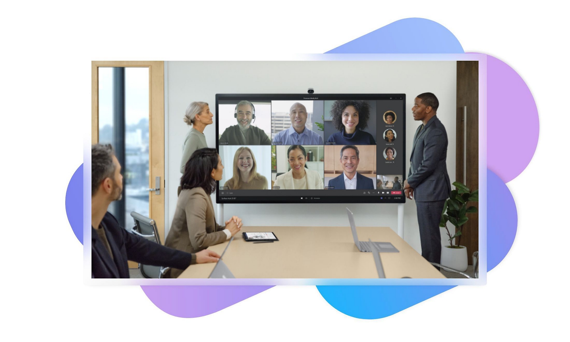 A group of people in a meeting room participating in a Teams call via the television mounted on the wall behind them.