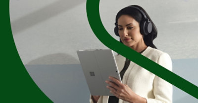 A person wearing over the ear headphones and using a tablet.