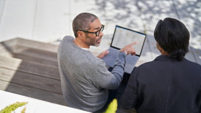 Eine Person mit Brille, die auf den Bildschirm eines Laptops zeigt.
