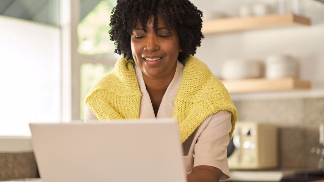 Woman smiling while using a Windows laptop.