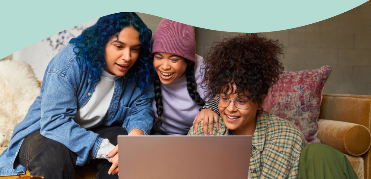 Photo of three young people looking at a laptop.