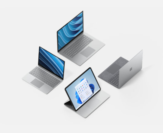 Four Surface devices with their lids open, three showing their screens.