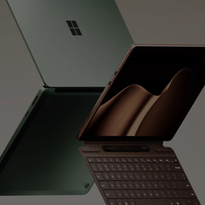 最新版 Surface 电脑，背靠背悬浮展示 — 一台 Surface Laptop 为翡翠绿，一台 Surface Pro 为沙漫金。