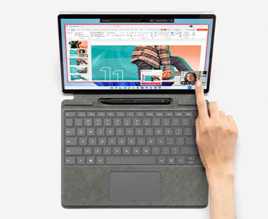 A hand points to the bottom right of the Surface Pro 8 in laptop mode.