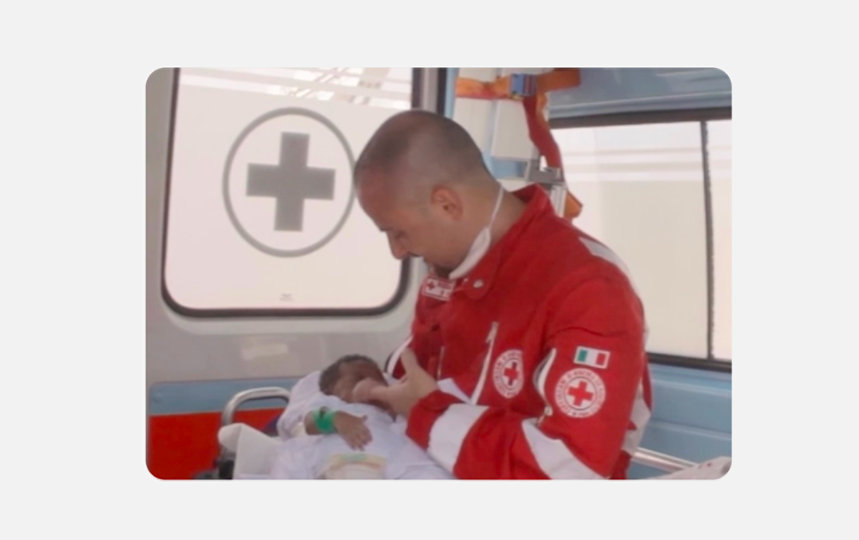 A Costa Rican Red Cross worker cradles an infant inside an ambulance, symbolizing compassion and humanitarian aid.