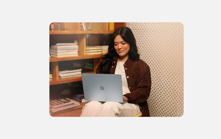 Person seated in a library with a 13 inch Surface Laptop on their lap.