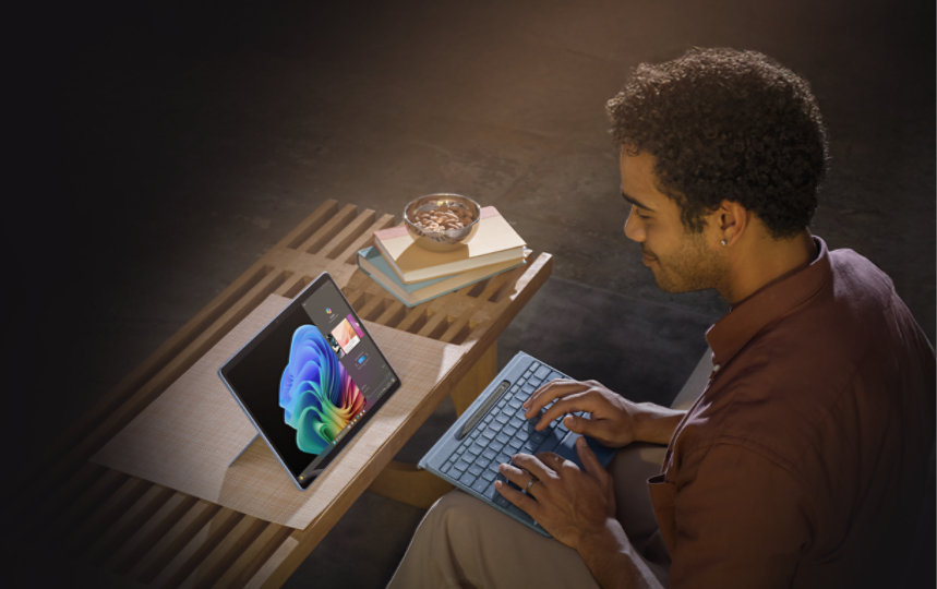 Person using Surface Pro 13-inch Copilot+ PC in Sapphire, holding the detached Pro Flex Keyboard. 