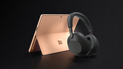 A 13-inch, Dune Surface Pro with a pair of black Sony wireless headphones.