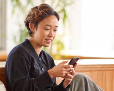 Een persoon op een bankje die naar haar telefoon kijkt