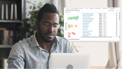 A man is working on a laptop. An overlay displays a dashboard with charts and data metrics in the background