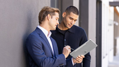 Two men standing outside while using a Platinum 12 inch Surface Pro with a Surface Pen.
