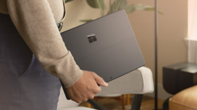 A man holding Surface Pro (11th edition) Copilot+ PC inside indoor setting.