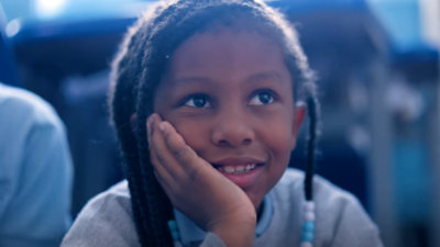 A young Black girl listens raptly to her teacher.